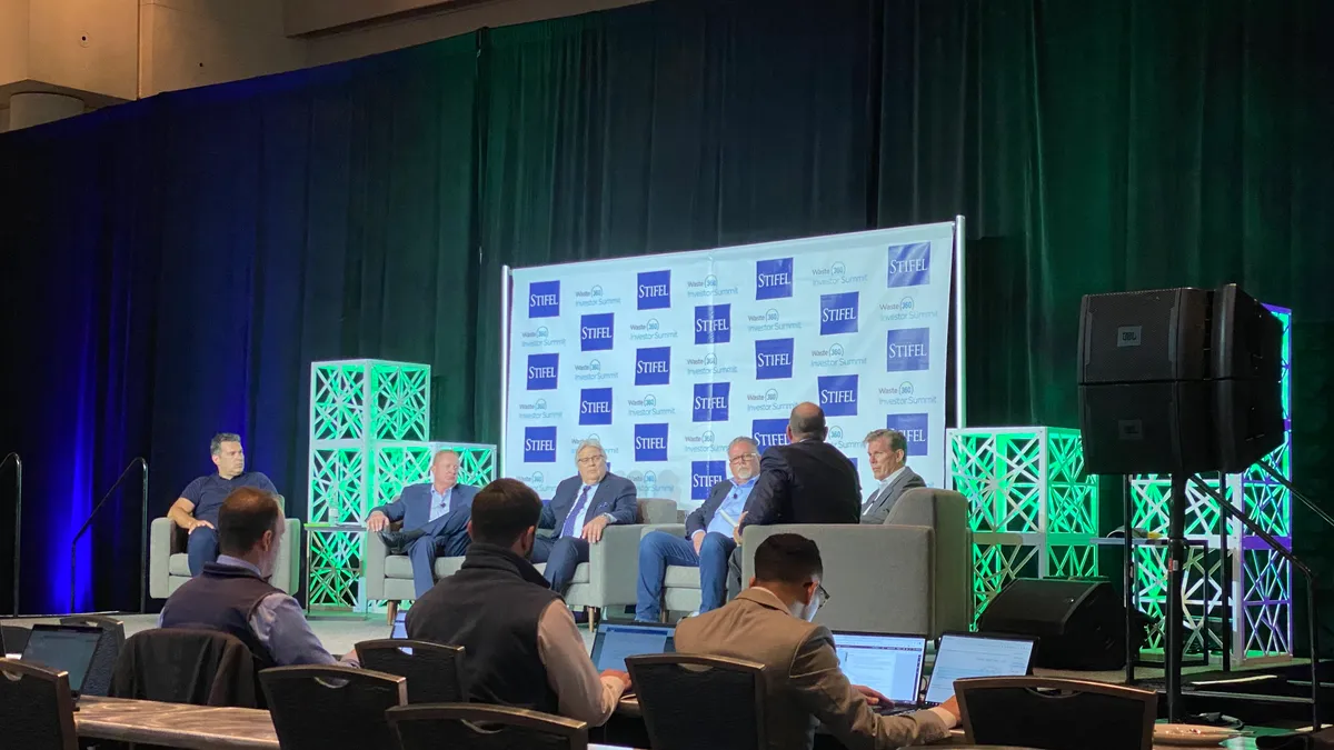 Multiple men sitting on a stage in a convention center