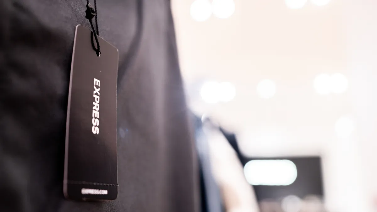 A label hangs from a pair of pants. The label reads "Express."