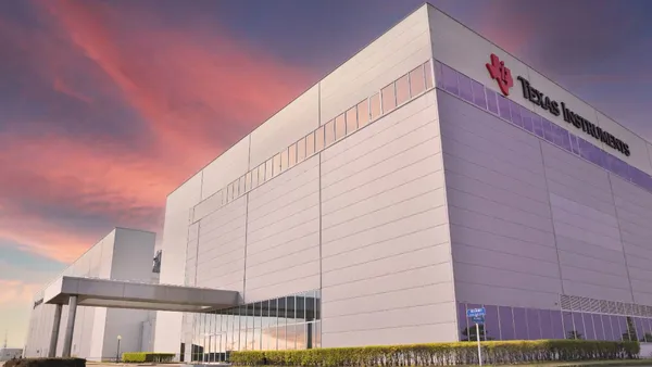 A an external corner of beige and iris purple building with the red and black Texas Instruments logo.