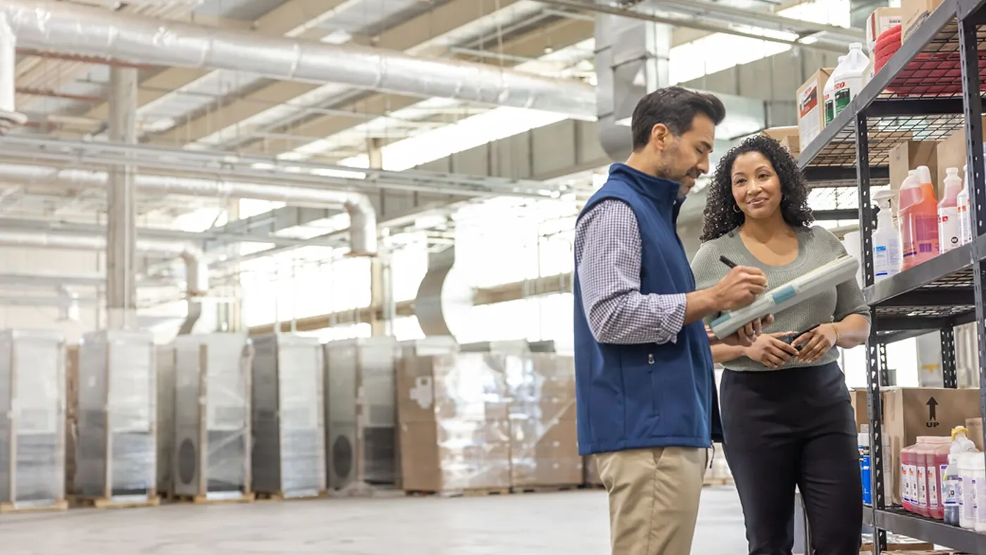 2 employees in a warehouse checking off items