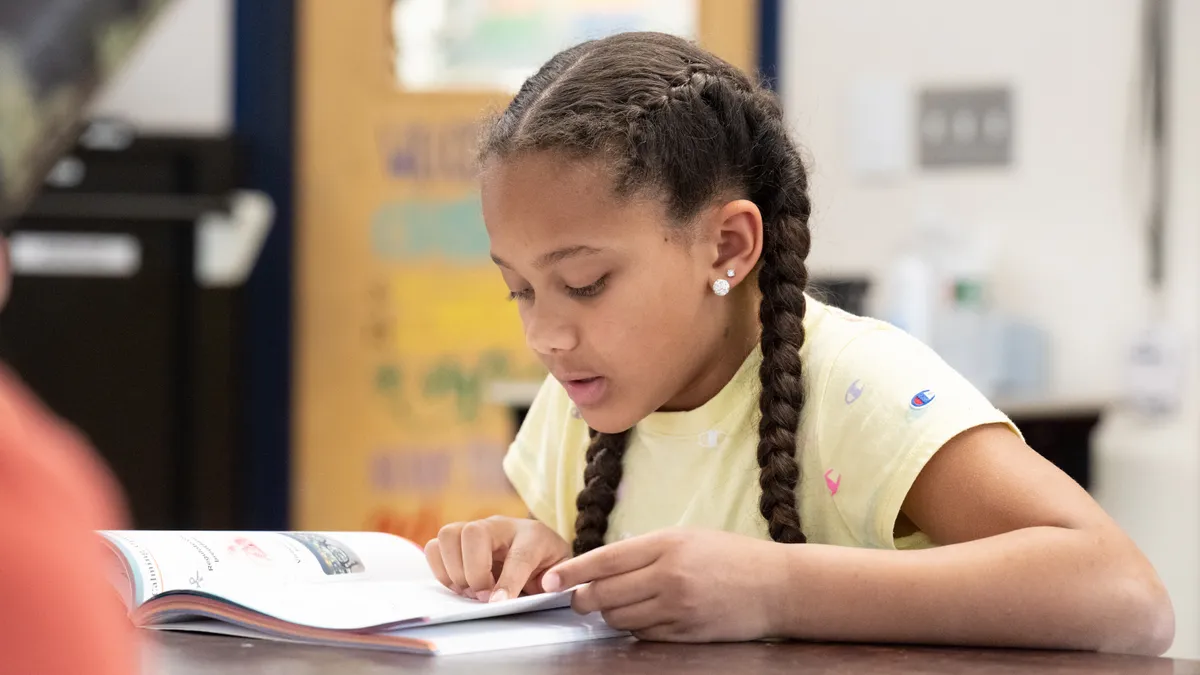 A kid reading a student workbook in a classroom