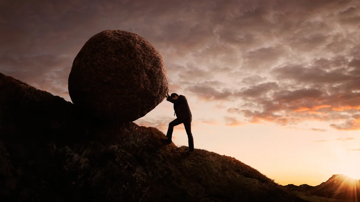 Person pushing large stone uphill