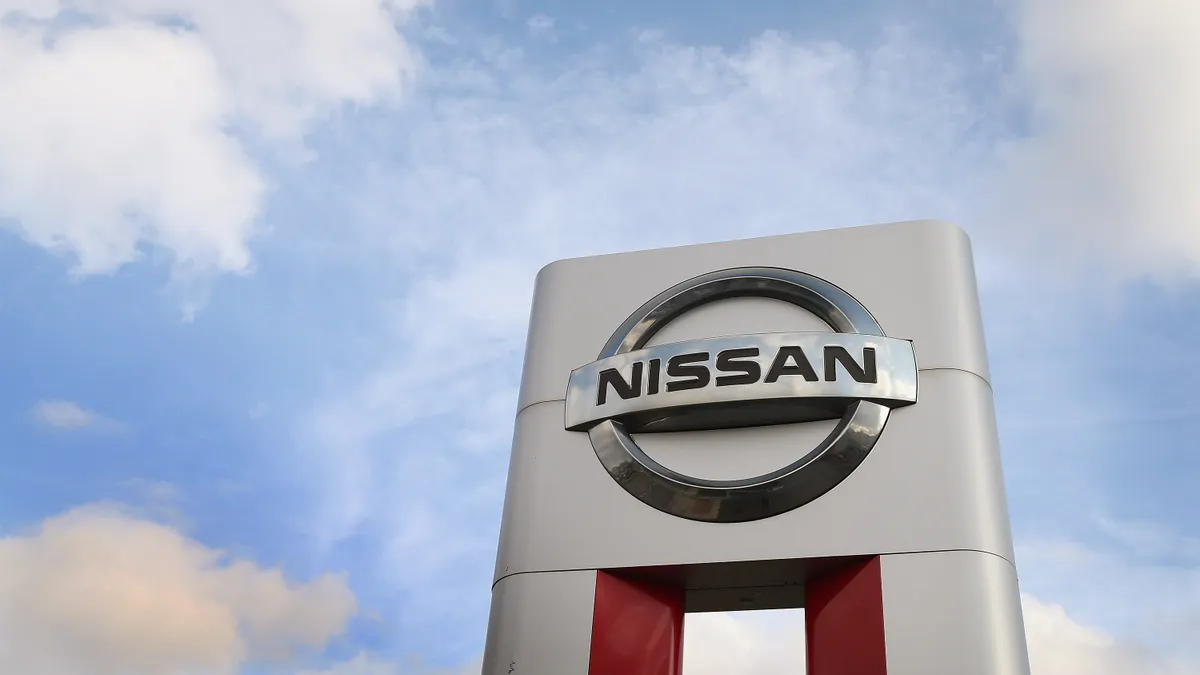 A picture of a Nissan dealer sign with a blue sky behind it