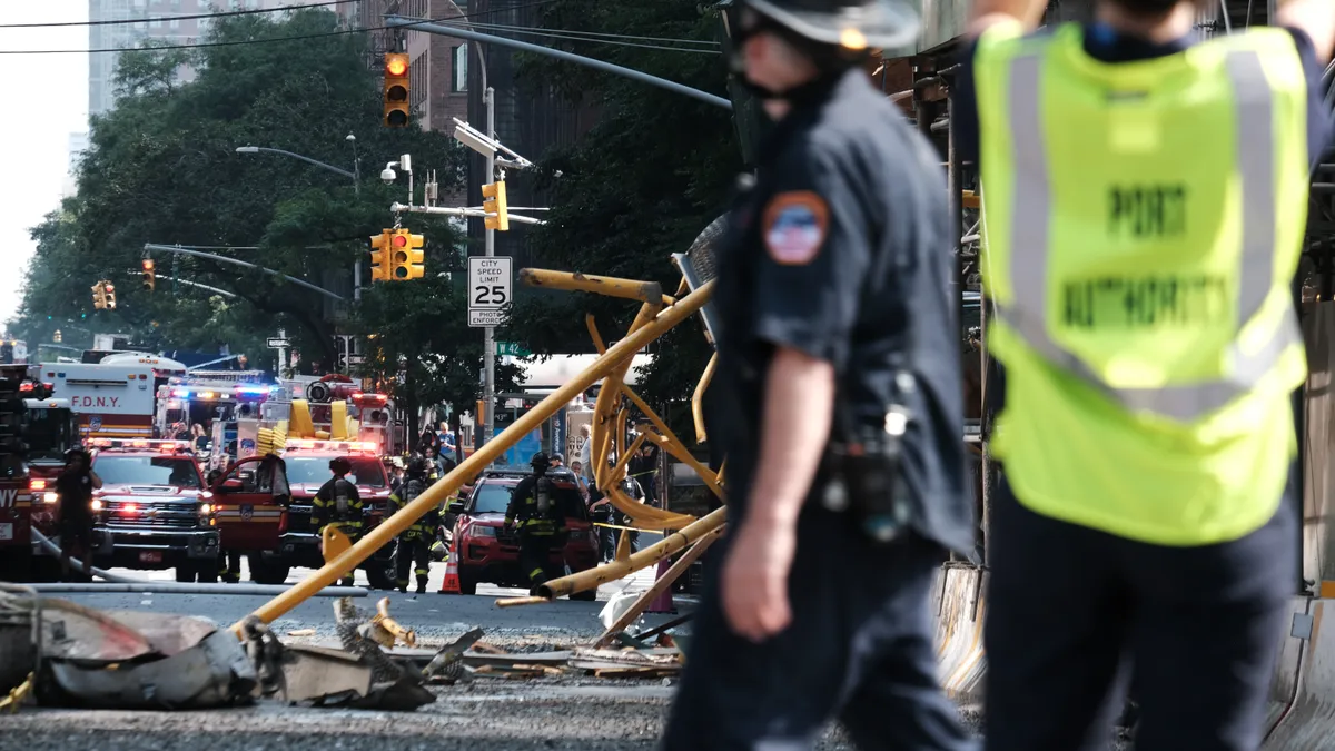 police walk in front of a collapse crane in a city street