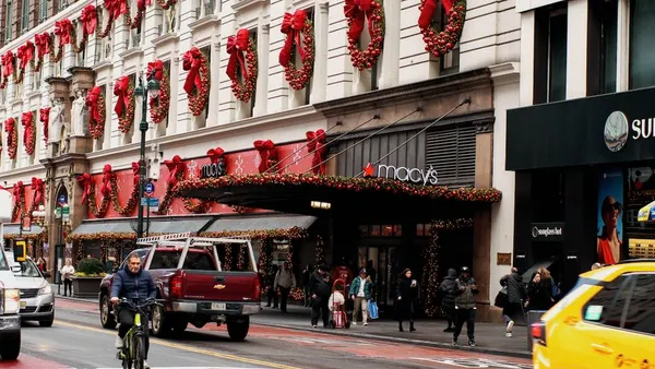 A cyclist and other traffic go by a department decorated for the holidays.