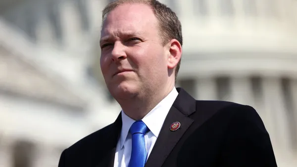 Lee Zeldin attends a press conference and squints into the sun.