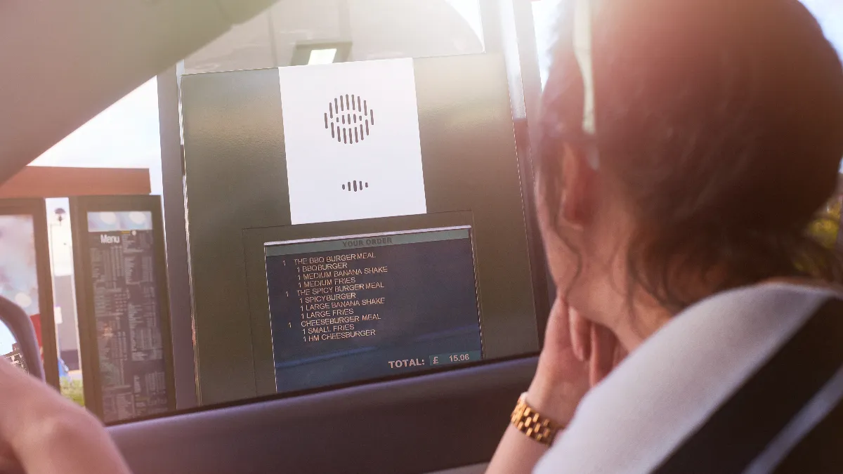 An image of a woman ordering at a drive-thru speaker box.