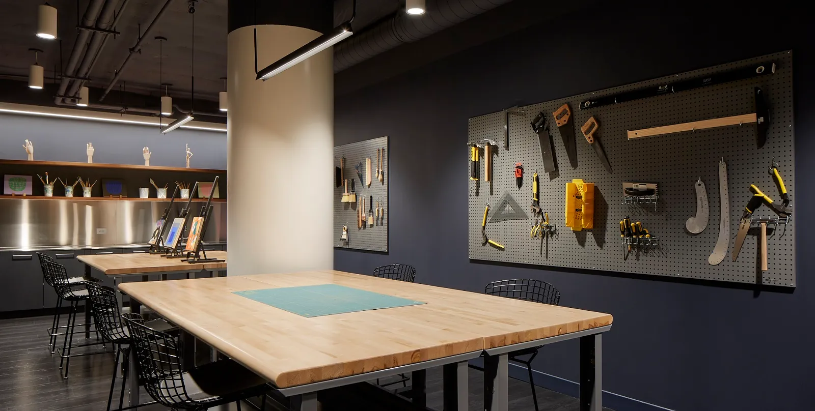 A room with a work table and a pegboard on the wall with various tools.