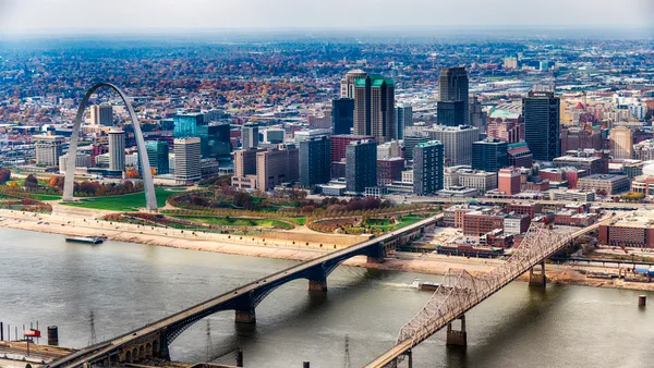 The St. Louis cityscape of buildings, bridges and Gateway Arch are shown from afar.