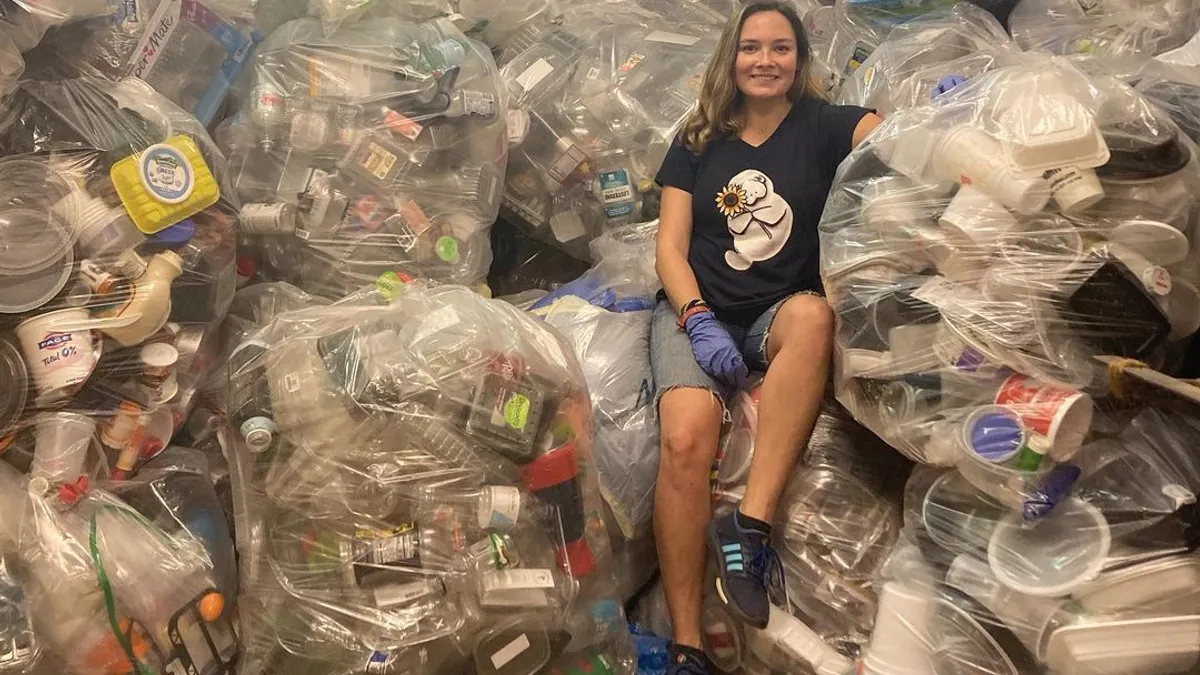 Person sitting on a stack of bags containing plastic packaging