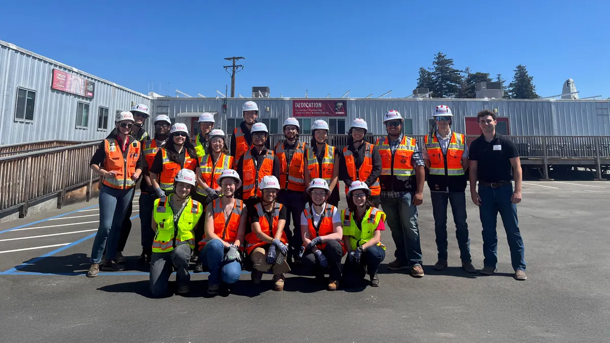 A group of people in construction safety gear pose for a photograph.
