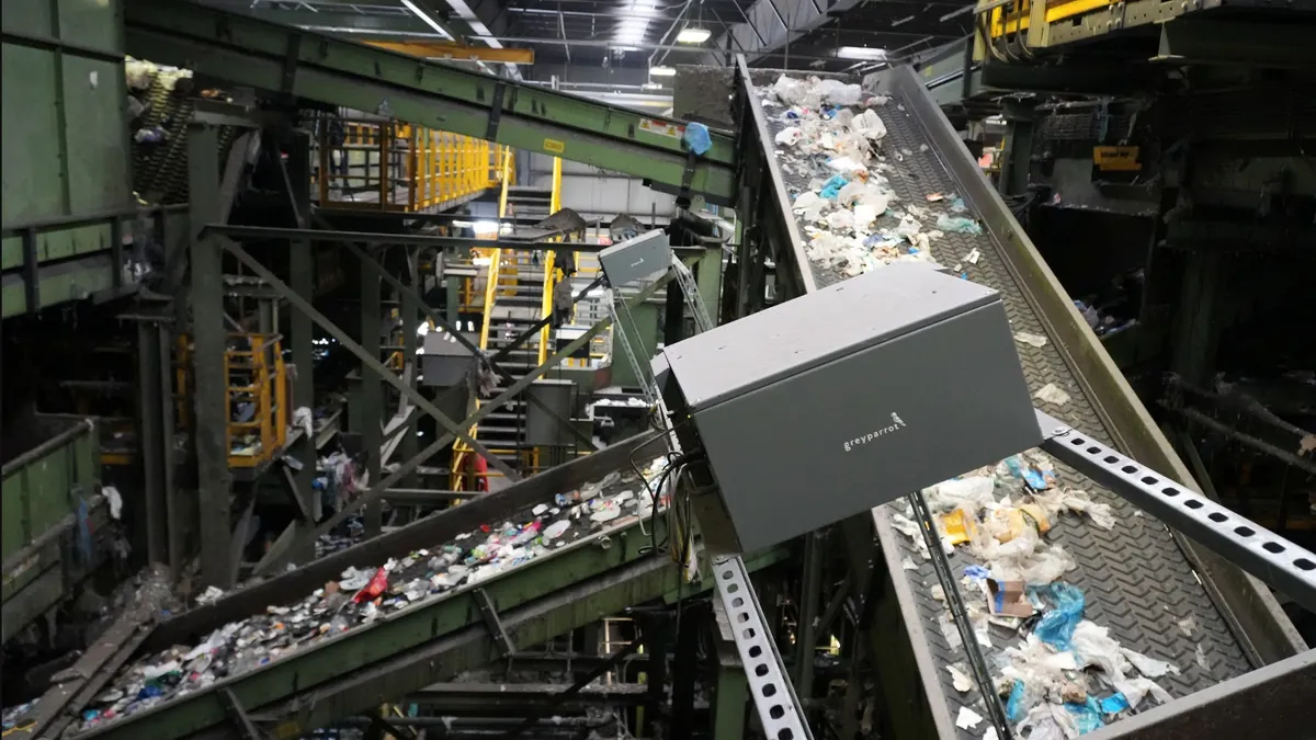 A grey box sits on top of a sorting line with mixed recyclables in a materials recovery facility.