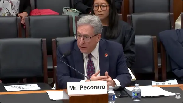 Man seated at a table with rows of chairs behind.