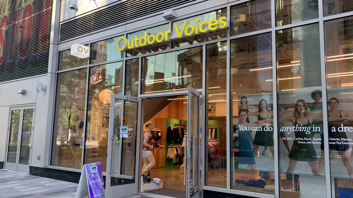 A storefront with main door open, a purple sign in front.