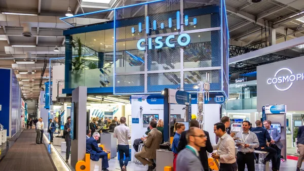 The display features Cisco's branding and showcases its latest innovations while attendees engage with the exhibit. 