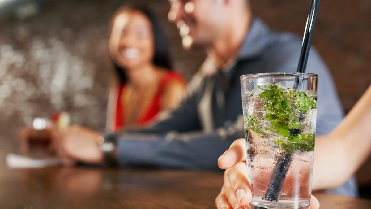 Cocktail Glass With Blurred Couple Behind - stock photo