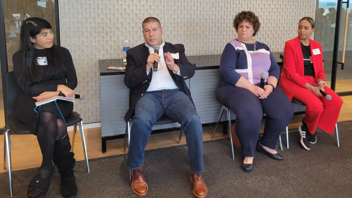 A group of four panelists in a conference room