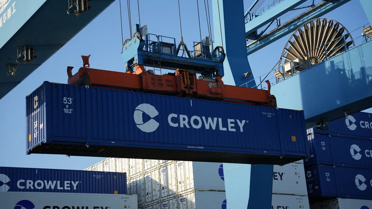 A 53-foot blue container being moved by a gantry crane.