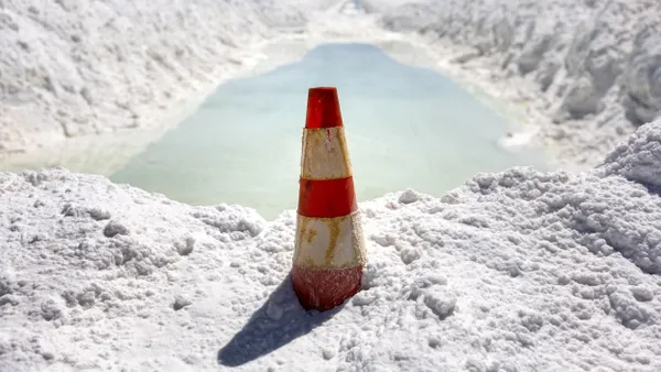Lithium-rich brine dries in an evaporation pond next to mounds of salt bi-product at a lithium mine