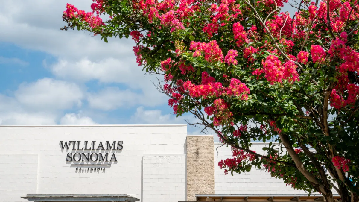 A tree with pink flowers stands in the foreground while a Williams-Sonoma storefront stands in the background.