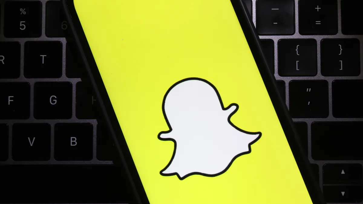 The Snapchat logo is displayed on a cell phone screen.