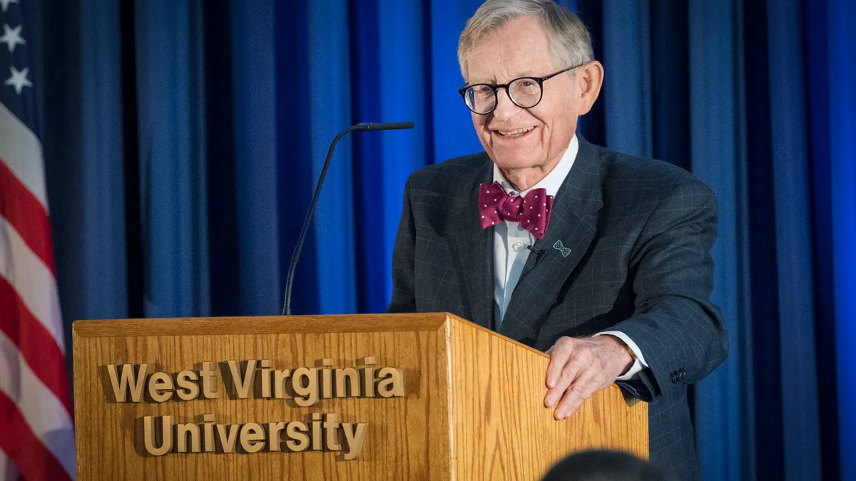 E. Gordon Gee, president of West Virginia University, wears a bowtie and suit and speaks at a podium.