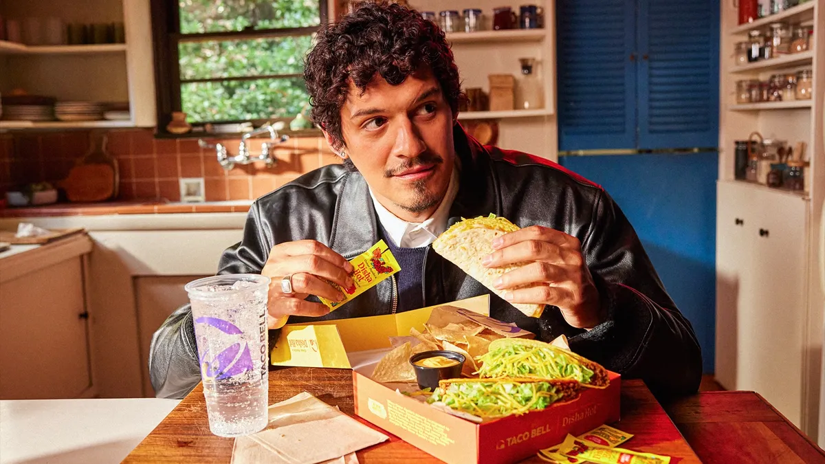 Omar Apollo holds Taco Bell items as part of a collaboration