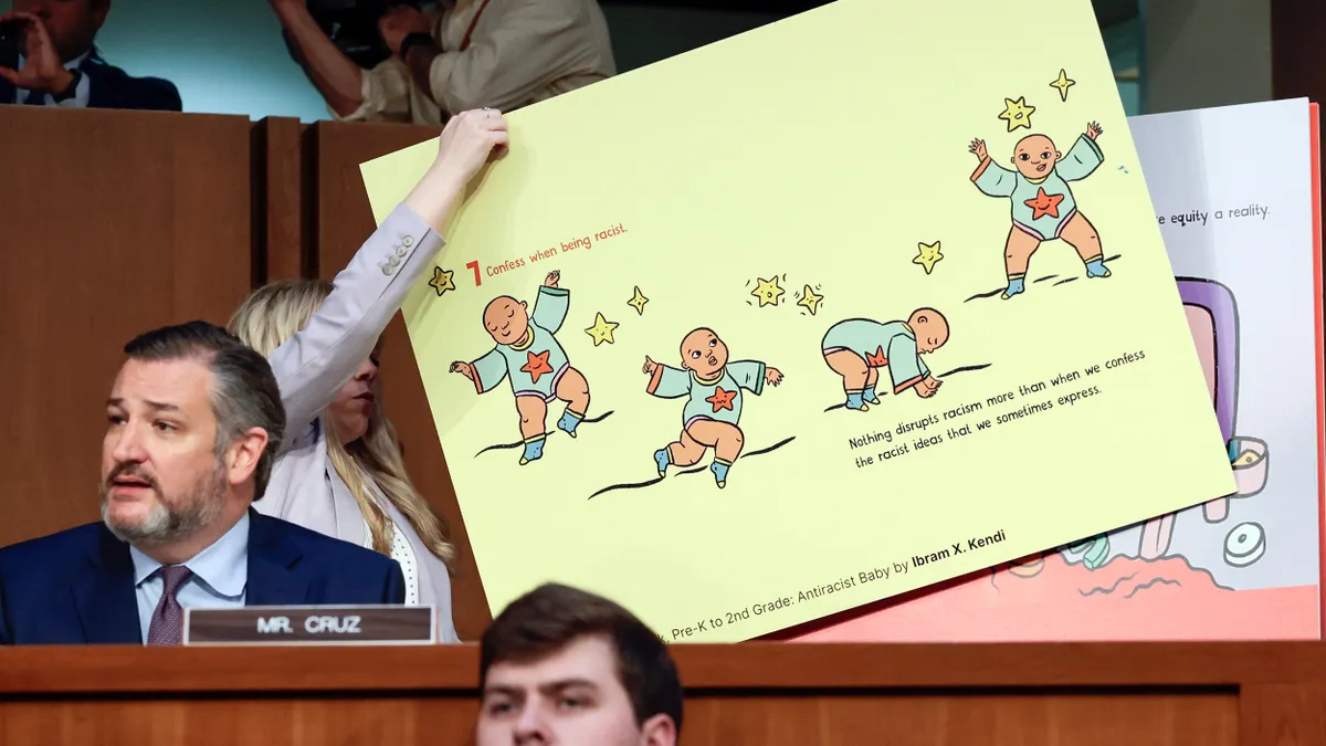 A person moves a large poster behind U.S. Senator Ted Cruz. The poster reads,"Confess when being racist; Nothing disrupts racism more than when we confess the racist ideas that we sometimes express."