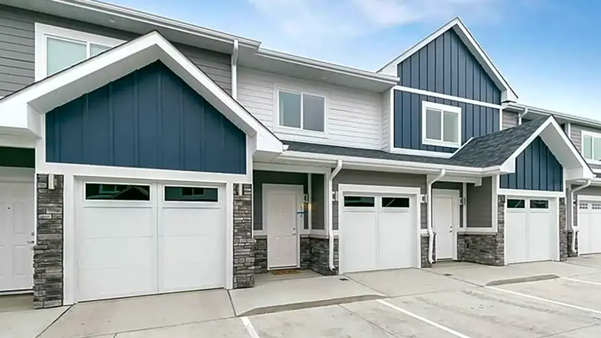 A two-level, multi-colored rental housing building with garages.