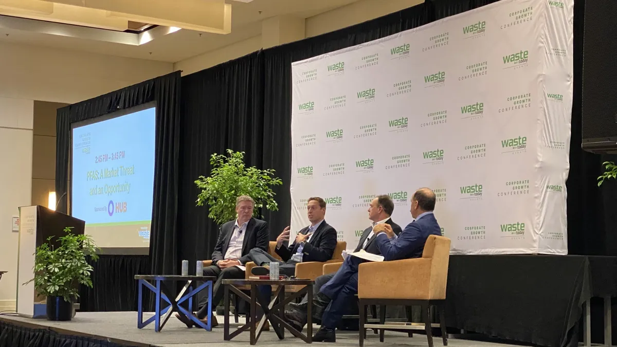 Three men are seated on a stage with a backdrop reading "Waste Today events" and "Corporate Growth Conference" behind them. One person in the center is speaking.