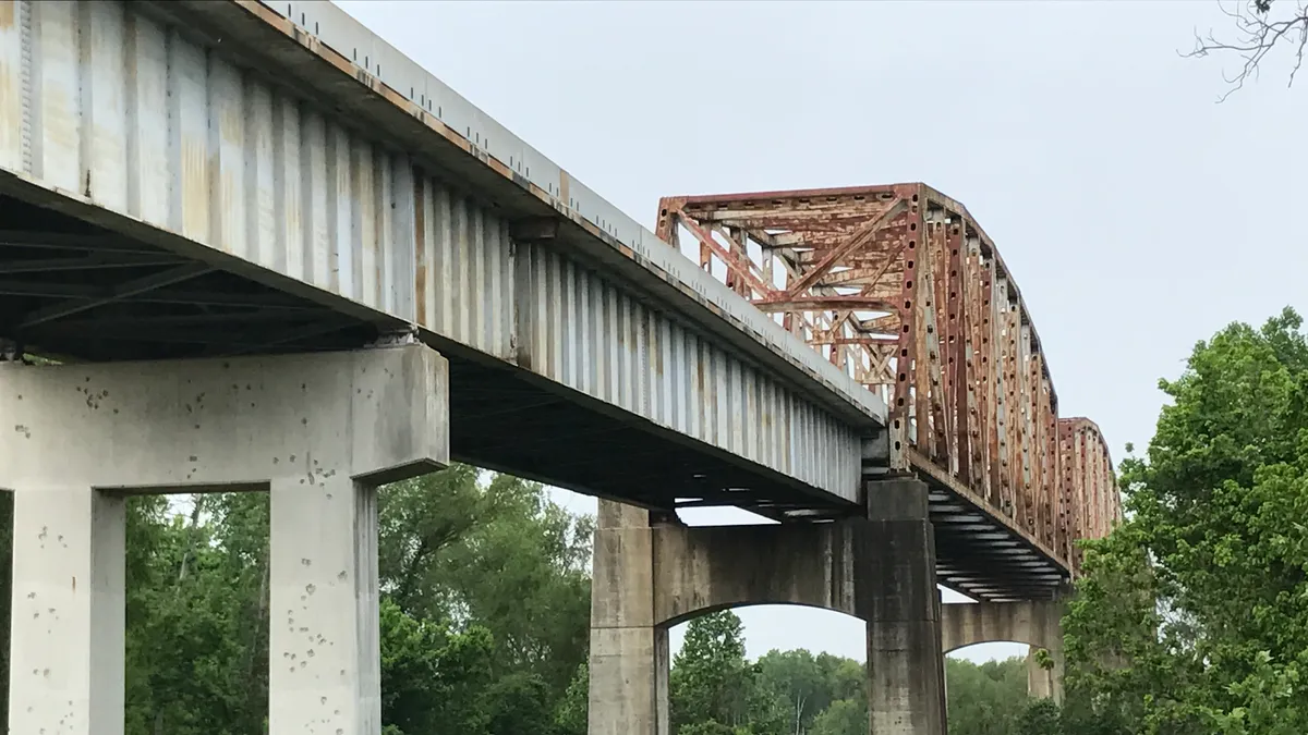 A view of a rusty bridge on concrete pillars.