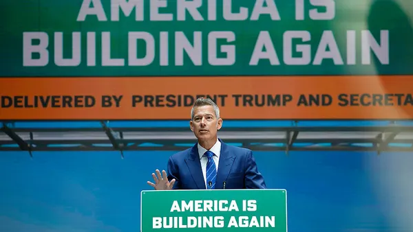 Transportation Secretary Sean Duffy stands at a podium, with sign reading "America is building again."