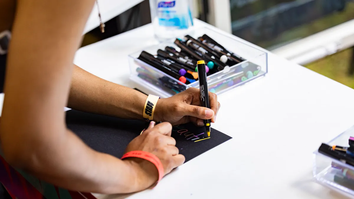 A person writing with a Sharpie pen.