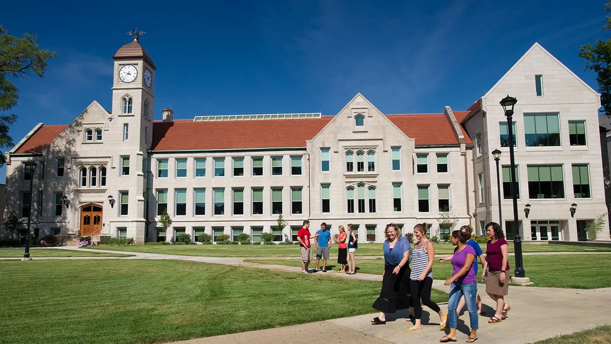 A group of people walk along a sidewalk outside of a Bradley University campus building.