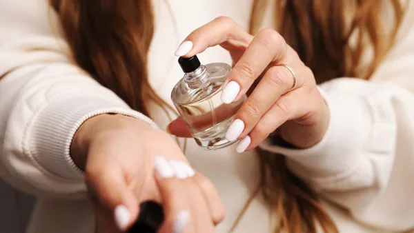 Woman applying perfume on wrist indoors.