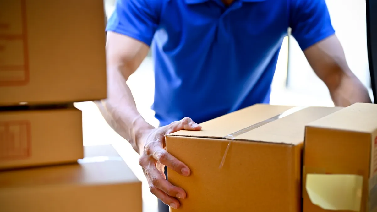 Close up view of delivery man in blue uniform organizing packages before handing package to customers