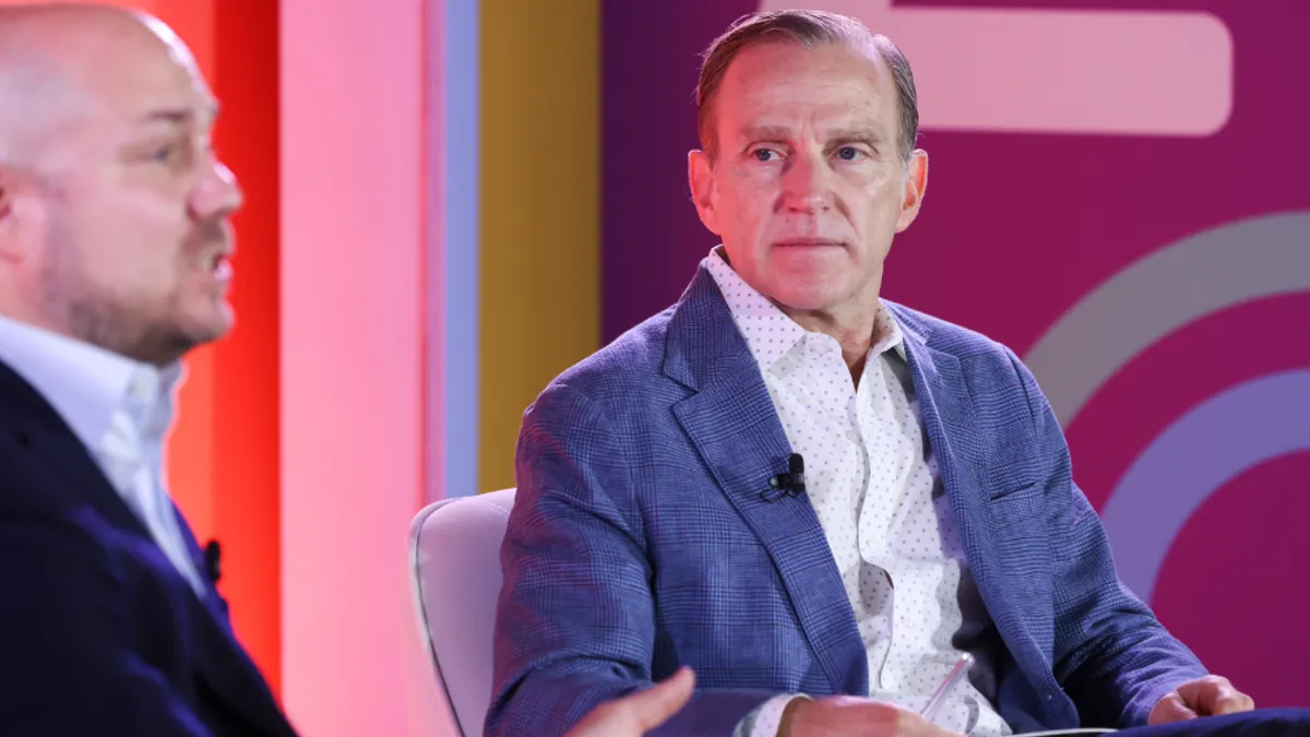 Two men sit on a colorful stage at Advertising Week 2024.