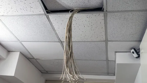 Plenum communications cable coming out of drop ceiling tiles in an office.