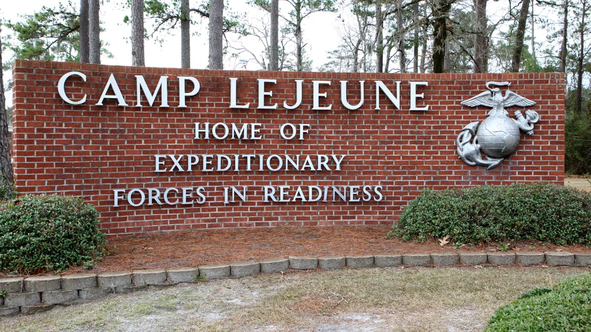 A red brick sign with "Camp Lejeune, home of expeditionary forces in readiness" in gray and an eagle, globe and anchor next to the letters.