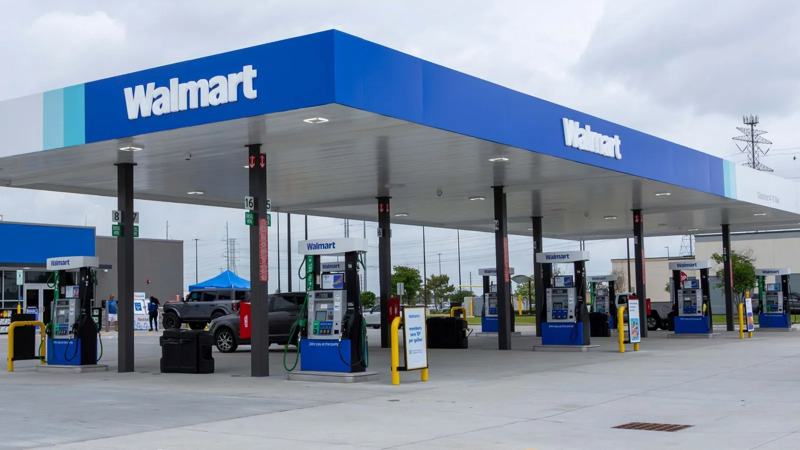 A gas station covered by a blue roof with signs that say "Walmart" in white letters.