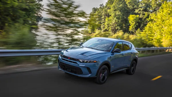 A blue 2024 Dodge Hornet GT on a road with trees in the background.