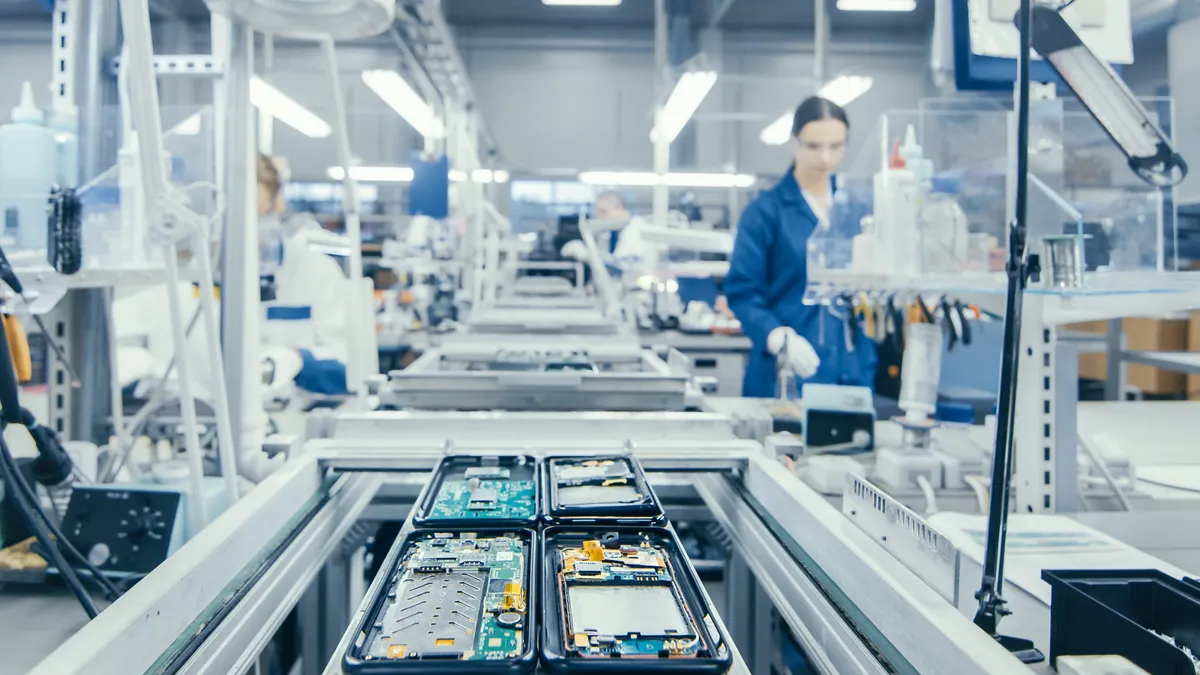 Shot of an Electronics Factory Workers Assembling Circuit Boards by Hand While it Stands on the Assembly Line
