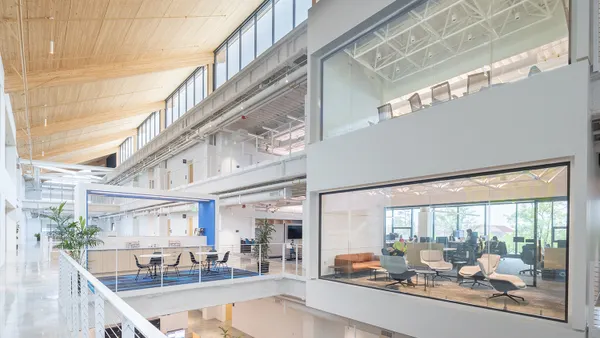 The interior of an open-concept office with abundant natural light and wood paneling.