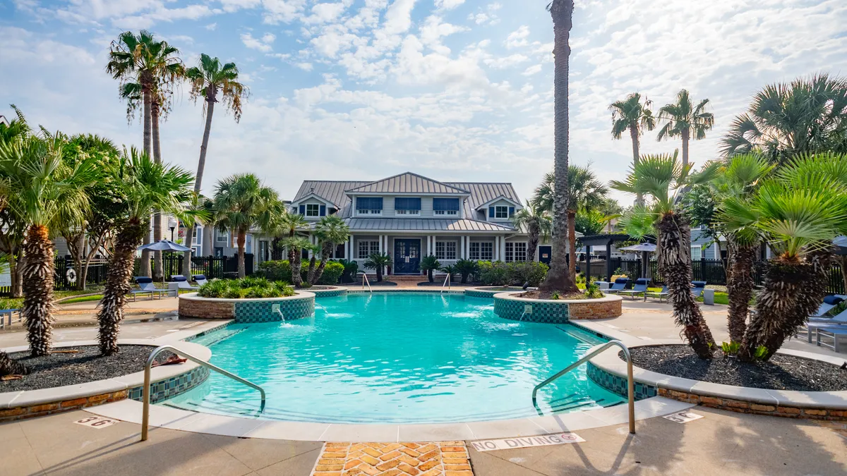 Garden-style apartment building with a pool in the foreground.