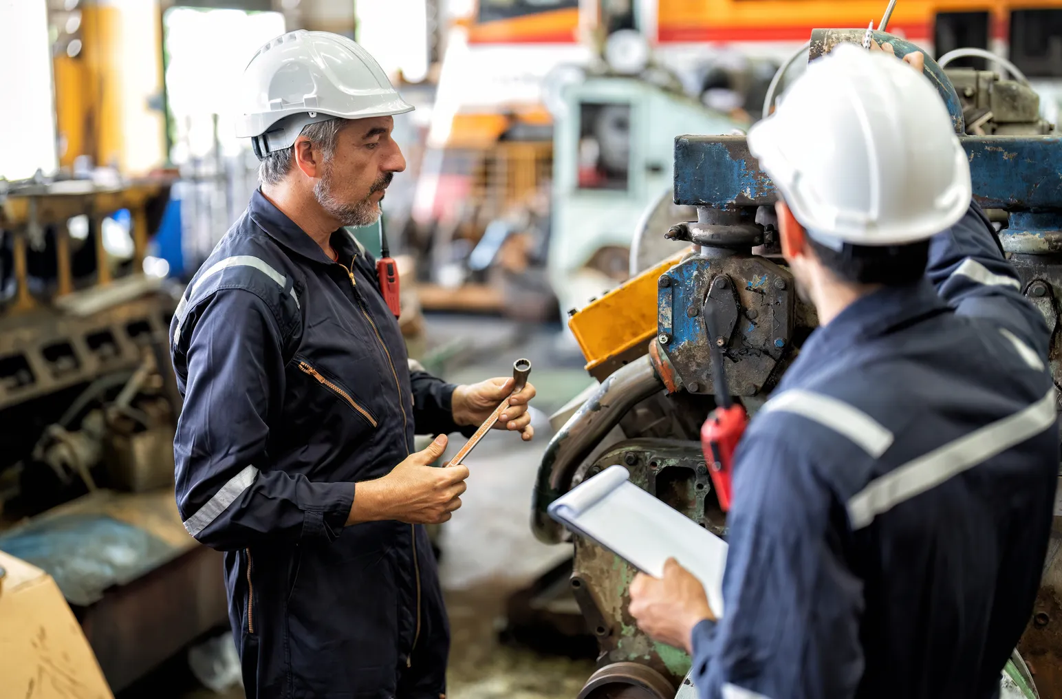 Two maintenance workers inspect a machine.