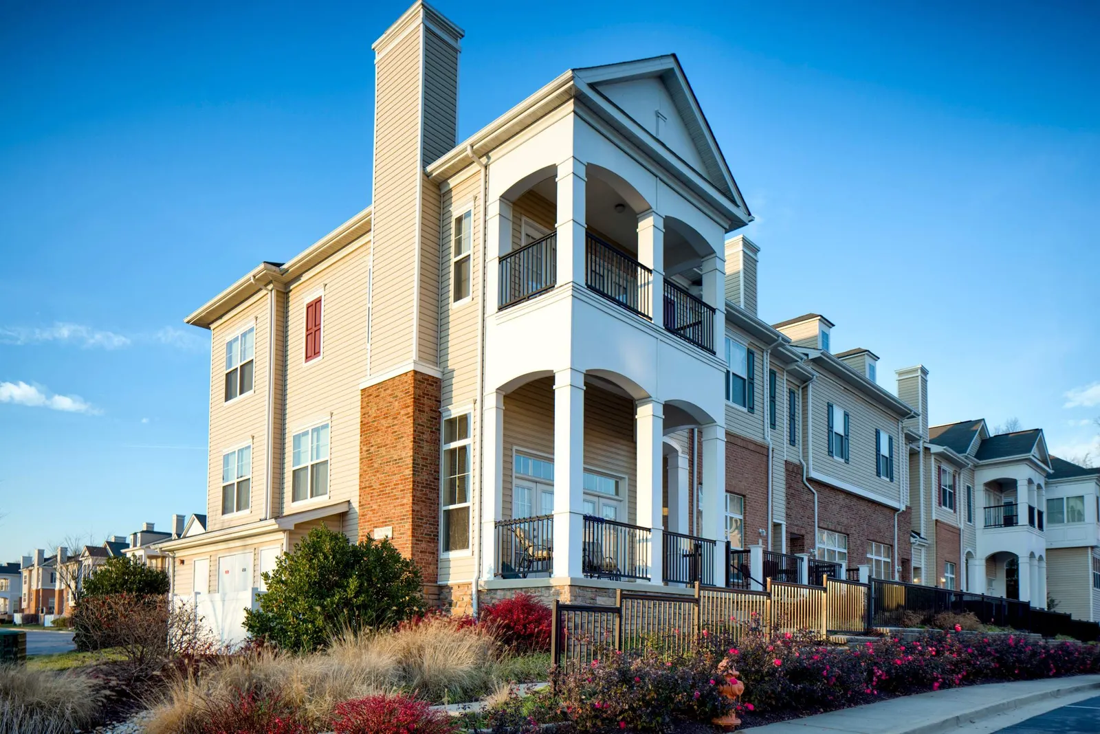 Side view of two-level, light-colored apartment property.