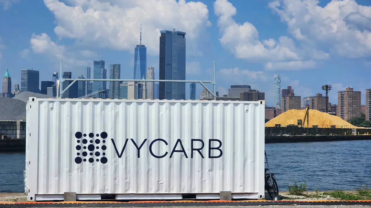 An image of a shipping container with Vycarb on the side and the New York City skyline in the background