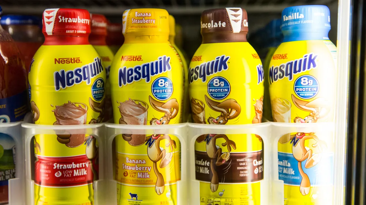 Different flavors of Nesquik milk are lined up in a fridge.