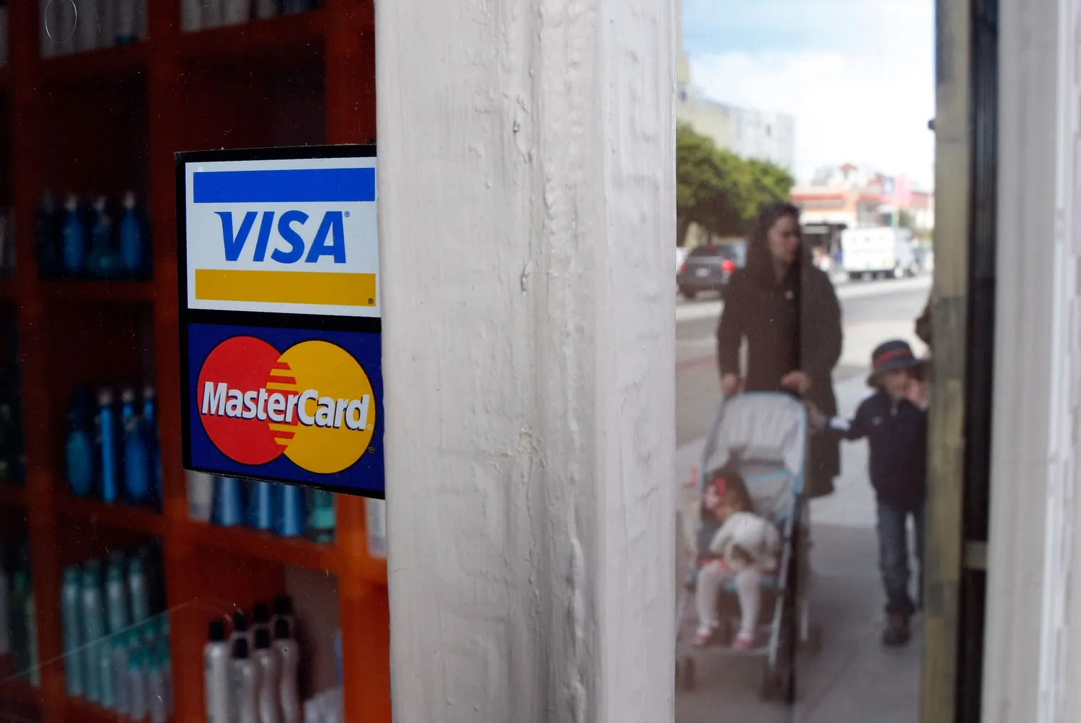 Stickers with the visa and mastercard logos on the exterior window of a store.