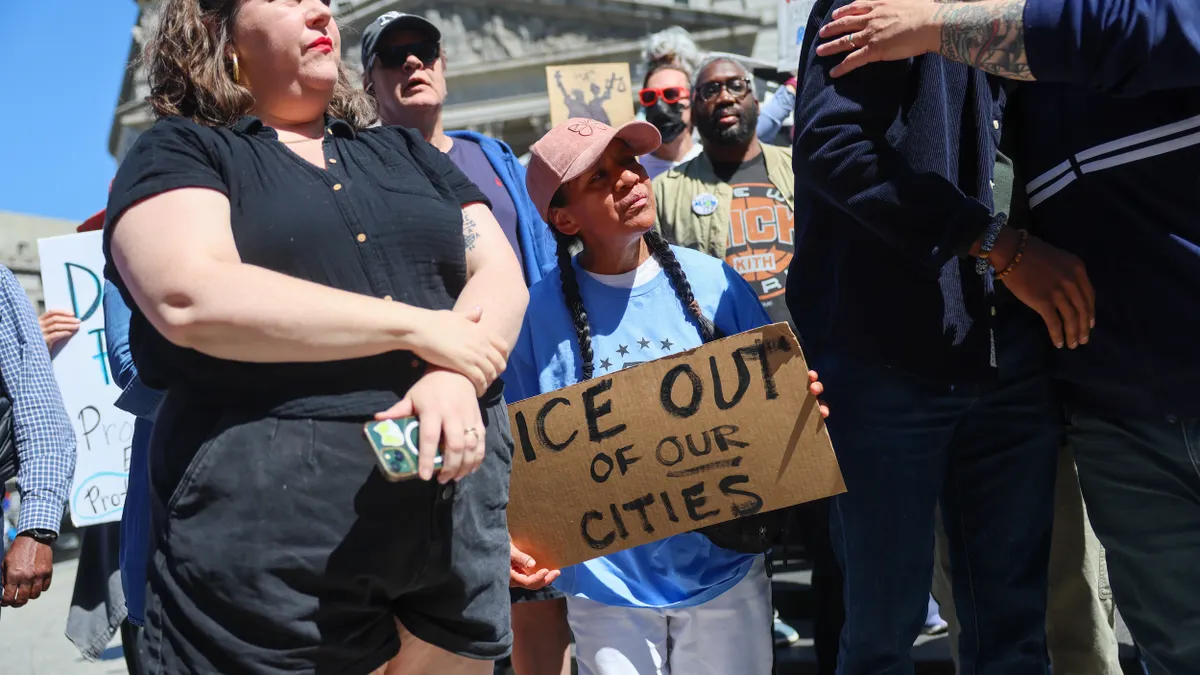 A crowd of protesters with signs. Sign reads "ICE out of our cities."